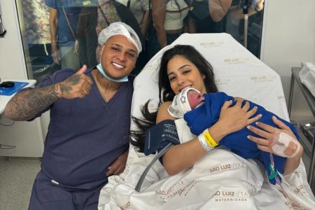 Pai e mãe com bebê no colo em hospital