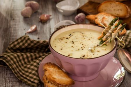 creme de aspargos em uma cumbuca rosa com fatias de pães