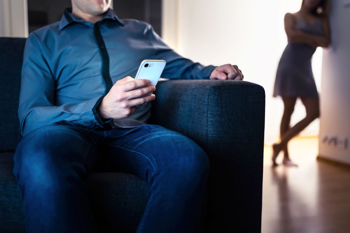 homem de gravata sentado em poltrona segurando o celular