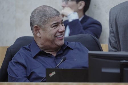 Imagem colorida mostra Milton Leite, homem negro, grisalho, sentado em uma cadeira de couro, sorrindo, olhando para seu lado esquerdo. Ele veste camisa azul. A imagem é de seu peito para cima - Metrópoles