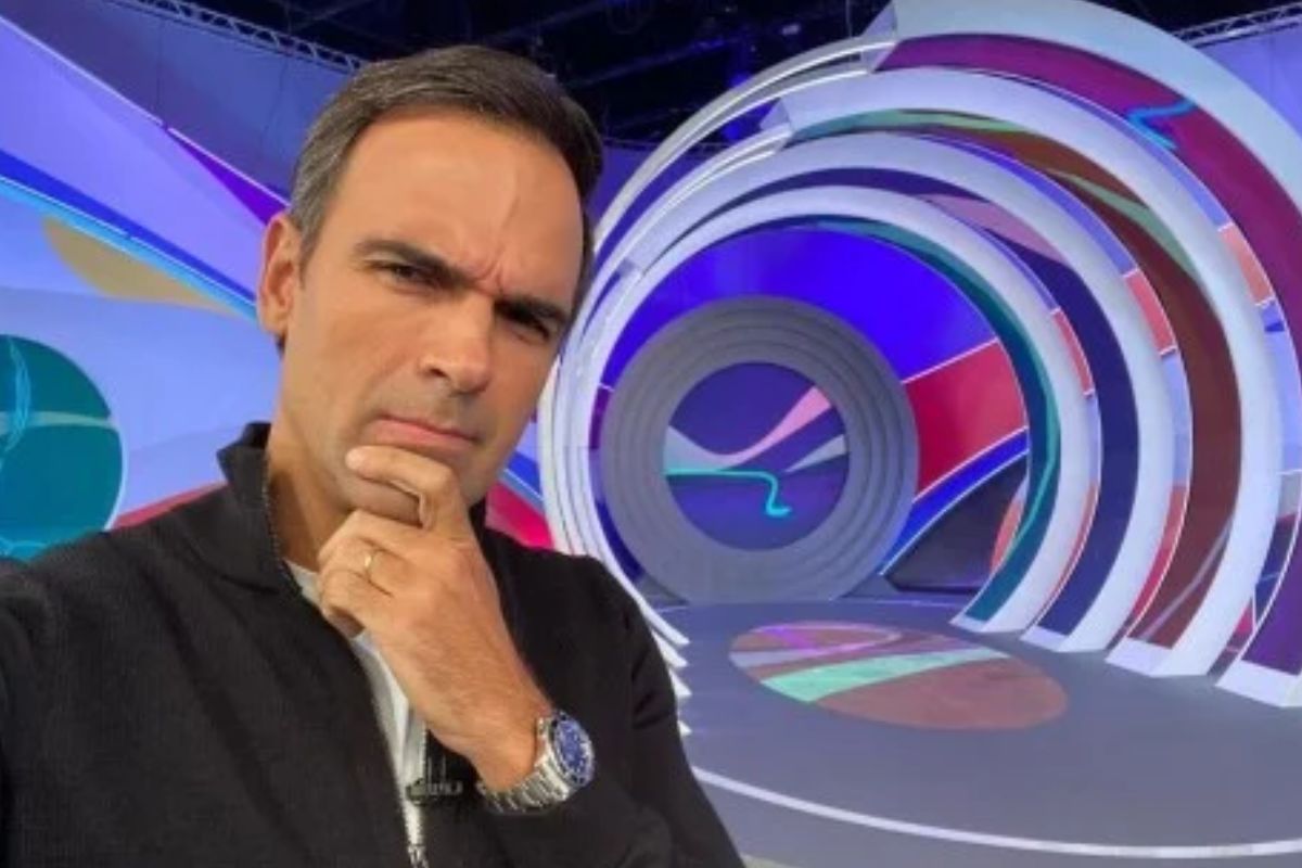 Foto colorida de Tadeu Schmidt fazendo pose pensativa no estúdio do BBB - Metrópoles