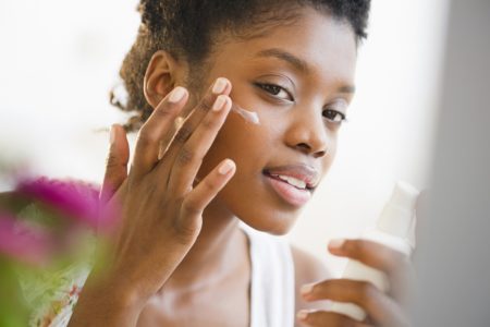 Fotografia mostra mulher negra aplicando filtro solar no rosto - Metrópoles