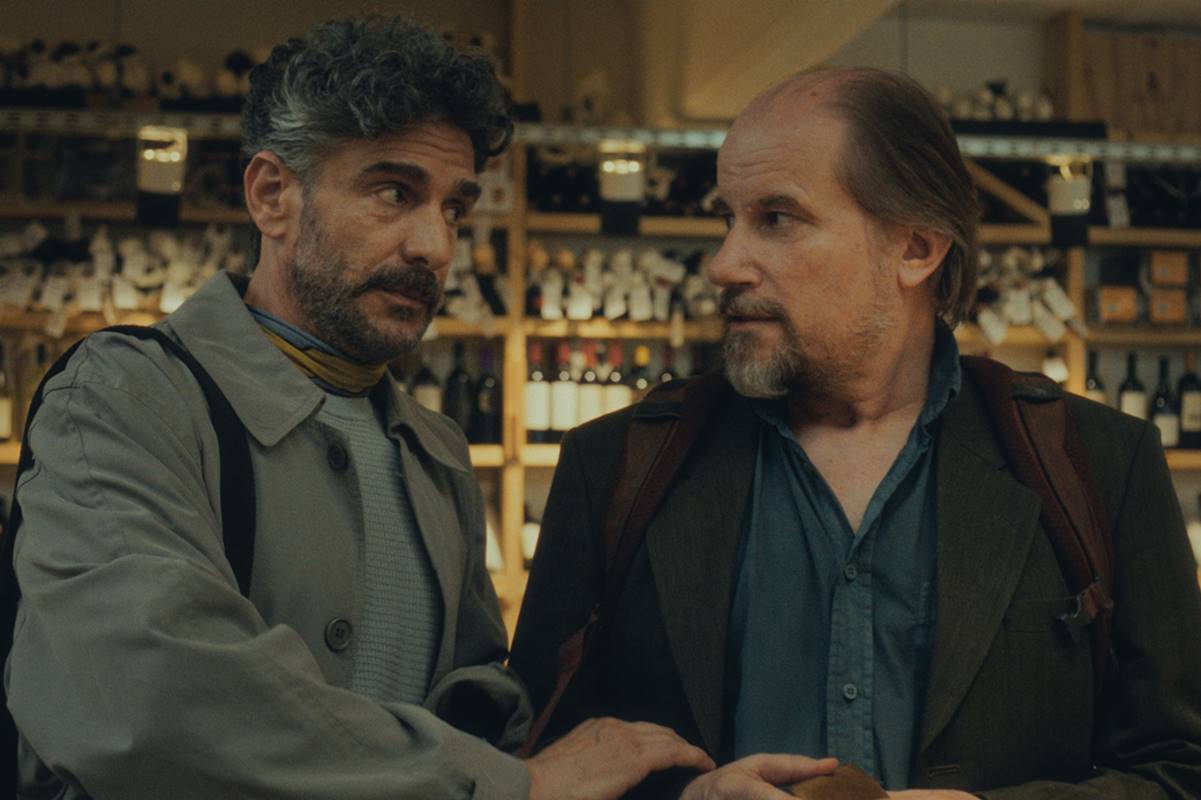Foto colorida de Marcelo Subiotto e Leonardo Sbaraglia em cena do filme Puan. Ao fundo, garrafas de vinho - Metrópoles