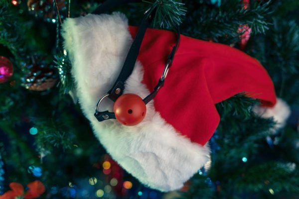 Foto colorida de um sex toy pendurado em uma árvora de Natal com um gorro de papai noel - Metrópoles