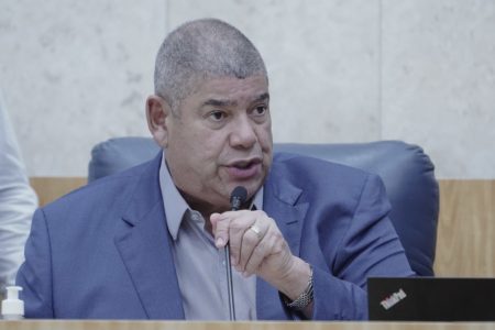 Imagem colorida mostra Milton Leite, homem negro, grisalho, de terno azul e camisa cinza, sentado na cadeira da presidência do plenário da Câmara, falando ao microfone. A foto é do peito para cima - Metrópoles