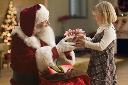 Imagem colorida de papai noel entregando presente para criança - Metrópoles