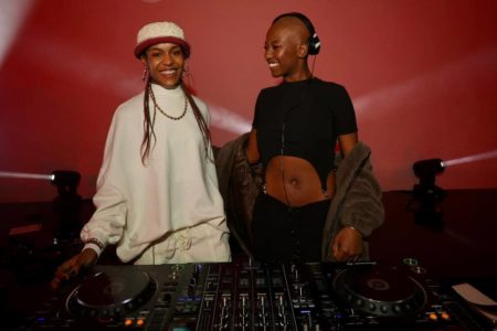 Duas mulheres com roupa branva e preta em frente a equipamentos de DJ - Metrópoles