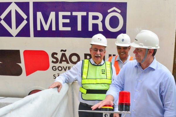 Foto colorida do governador Tarcísio de Freitas, de capacete e camisa azul, apertando botão em canteiro de obra do Metrô - Metrópoles