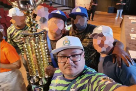 Foto colorida com homem de boné branco, segurando troféu, rodeado por outros homens - Metrópoles