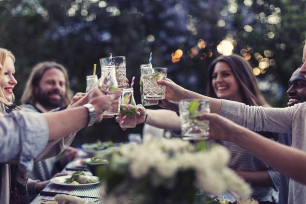 Imagem colorida mostra um pequeno grupo com homens e mulheres brindando com drinques. Eles estão sorrindo - Metrópoles