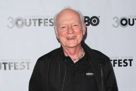Foto colorida de Mickey Cottrell com blusa preta e sorrindo para a câmera - Metrópoles