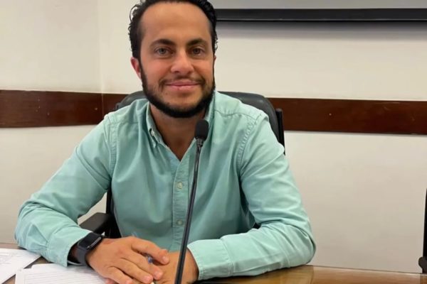Thammy Miranda posa, sentado, com um meio sorrido, em frente a um microfone e segurando uma caneta - Metrópoles