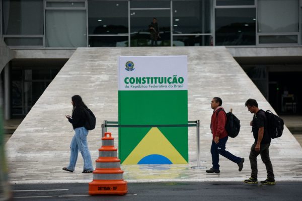 Pessoas passam em frente à réplica da Constituição colocada em frente ao Palácio do Planalto