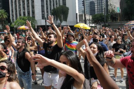 Imagem colorida mostra bloco de rua no Carnaval de SP, com grupo de pessoas dançando e sorrindo na rua - Metrópoles