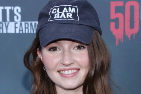 Kaitlyn Dever usando boné e sorrindo em tapete vermelho - Metrópoles