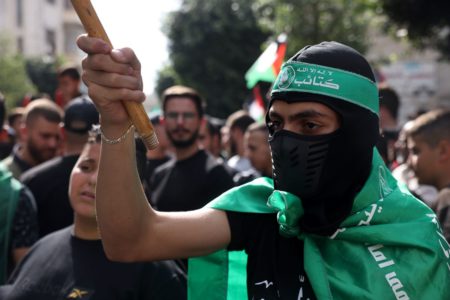 Imagem colorida mostra militantes do Hamas usando bandana e coberto com a bandeira do grupo - Metrópoles
