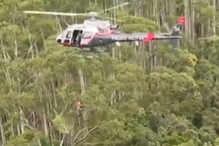 Imagem de PM descendo de rapel de helicóptero em área de mata - Metrópoles