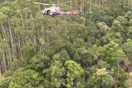 Foto colorida de helicóptero da PMSP sobrevoando área onde helicóptero caiu