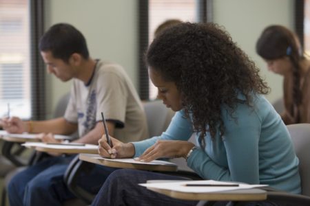 Imagem colorida de estudantes escrevendo no papel - Metrópoles