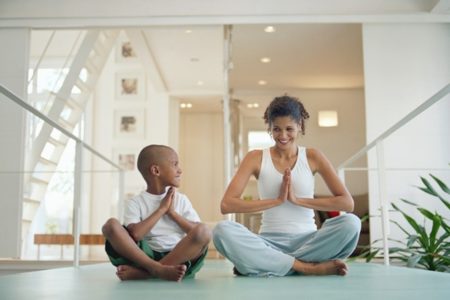 Menino sentado ao lado de mulher em posição de yoga - Metrópoles