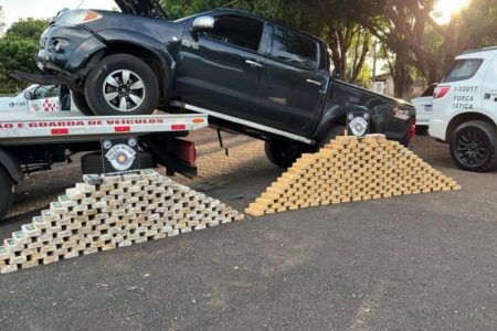 Imagem colorida mostra pacotes de drogas na frente de um carro apreendido pela Polícia Militar (PM); um agente da PRF foi detido - Metrópoles