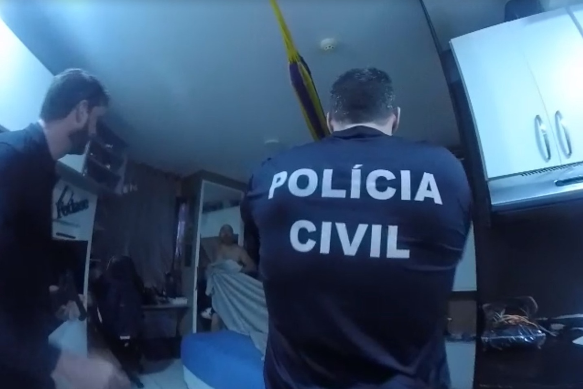 Policiais civis observam homem nu enrolado com lençol