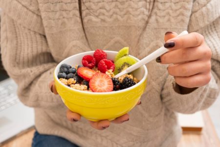 mulher segurando um bowl amarelo com frutas diversas