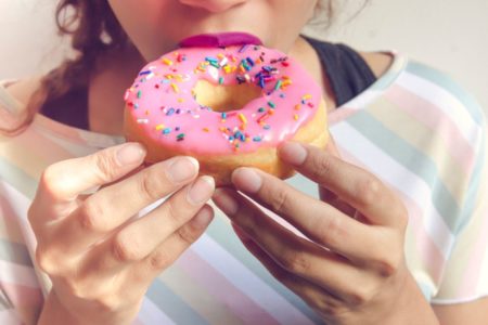 mulher comendo um donut rosa