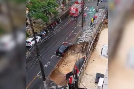 Imagem colorida mostra cratera aberta em calçada de prédio em obra após tempestade em Santos - Metrópoles