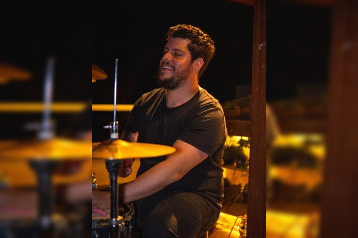 Imagem colorida de homem com camisa preta tocando bateria