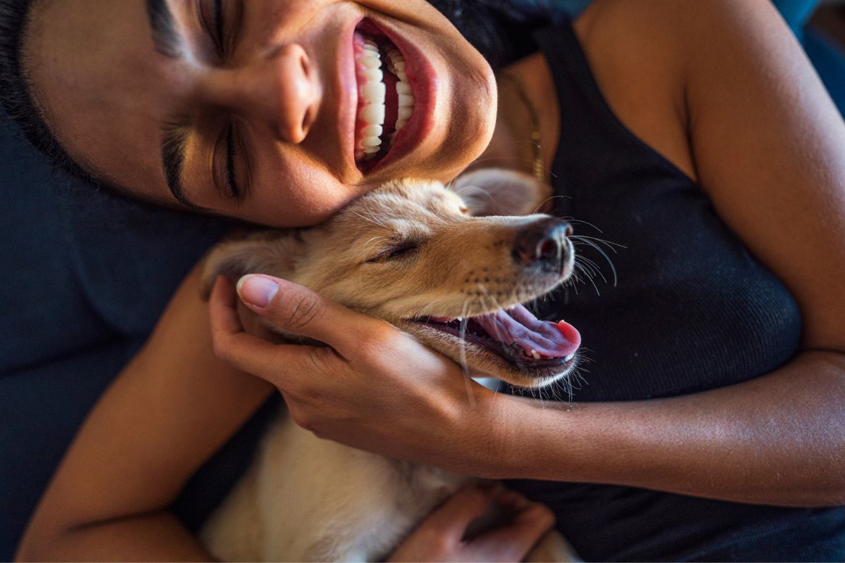 mulher sorrindo abraçando um cachorro