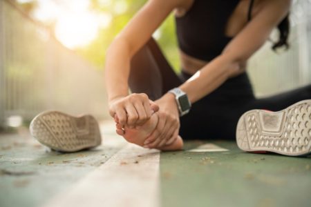 Mulher sentada no chão com Dores nos pés após trabalho ou corrida