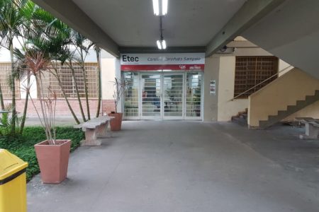 Imagem de entrada de escola, com corredor e uma porta de vidro - Metrópoles