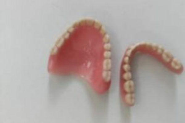 Imagem mostra par de dentaduras em fundo branco - Metrópoles