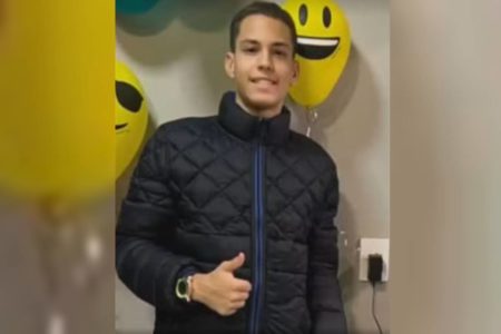 Jovem de 18 anos espancado na porta de hotel em Taguatinga. Jovem de casaco preto balões de smile ao fundo - Metrópoles