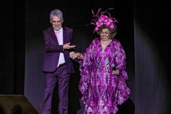 Chico Buarque e Alcione em cima de palco. Cantora usa roupa roxa - Metrópoles