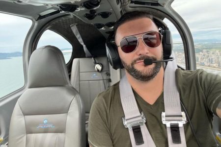 Imagem colorida mostra Mikael Minatti, homem de óculos escuros em um avião - Metrópoles