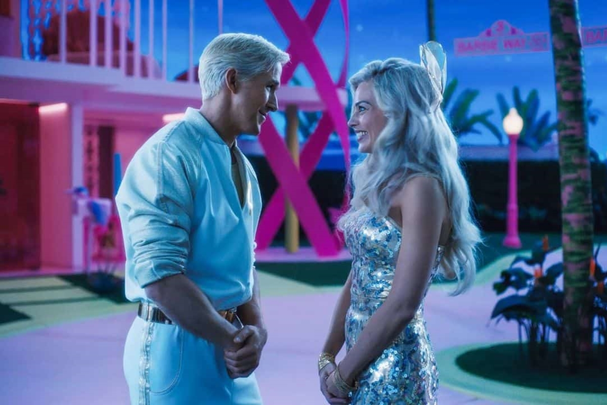 Trecho do filme Barbie. Na imagem, Ken e Barbie conversam. Ele usa camisa branca e ela está com um vestido brilhante - Metrópoles