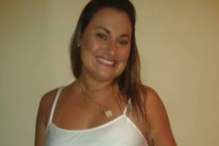 Imagem colorida mostra Dayane Isabel Roncari, uma mulher branca, de cabelos loiros, vestindo uma camiseta regata branca, sorrindo para a câmera - Metrópoles