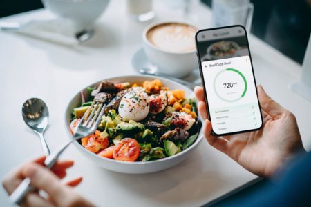 Foto colorida de um prato de comida e um celular - Metrópoles