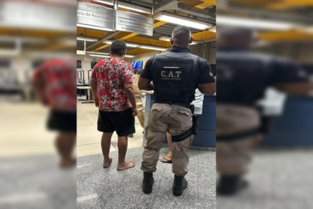 Imagem colorida de homem de camisa vermelha sendo preso- Metrópoles