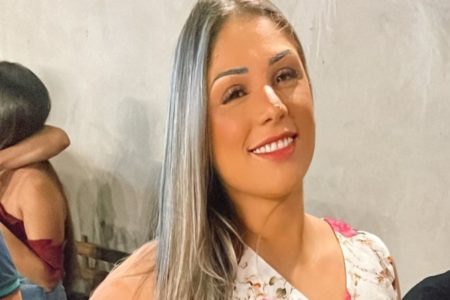 Mulher branca com cabelos loiros lisos veste blusa com estampa floral