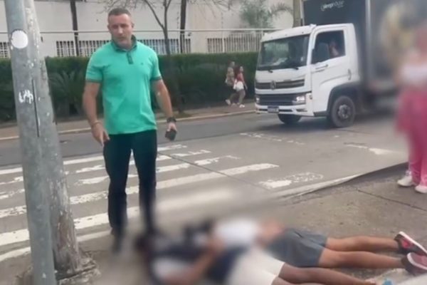 Fotografia colorida mostra o deputado Delegado Palumbo (MDB-SP), vestindo camisa verde e calça jeans, em pé, e dois homens amarrados deitados ao chão, de barriga para baixo e com os rostos ocultos em rua da Barra Funda, em SP