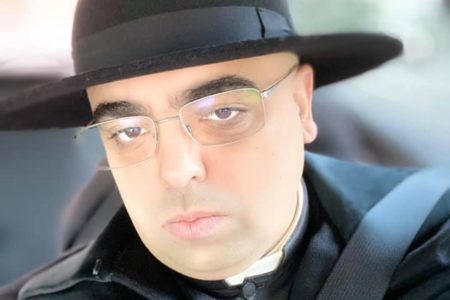 Foto colorida do padre José Eduardo de Oliveira e Silva, de óculos e chápeu preto