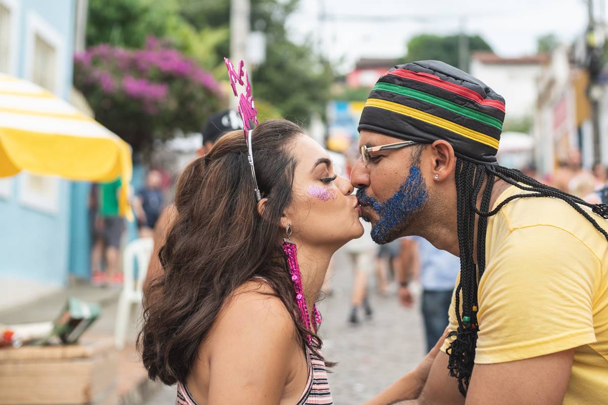 Foto colorida de um casal se beijando durante o bloco de rua no Carnaval - Metrópoles