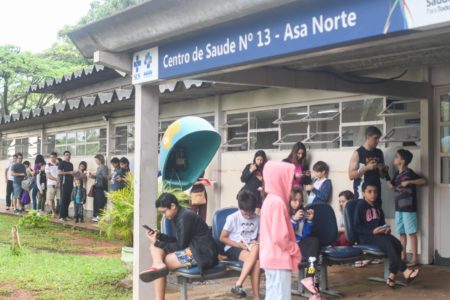 Imagem colorida de pessoas em fila, em frente à Unidade Básica de Saúde (UBS) 13 da Asa Norte