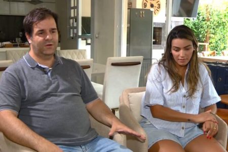 Imagem colorida de homem de camisa escura e mulher de camisa branca sentados concedendo entrevista - Metrópoles