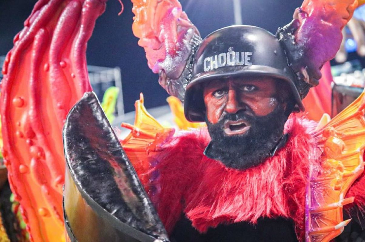 Imagem de homem fantasiado de policial com pinturas e adornos de demônio - Metrópoles