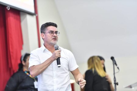 Fotografia colorida de homem discursando segurando microfone na mão