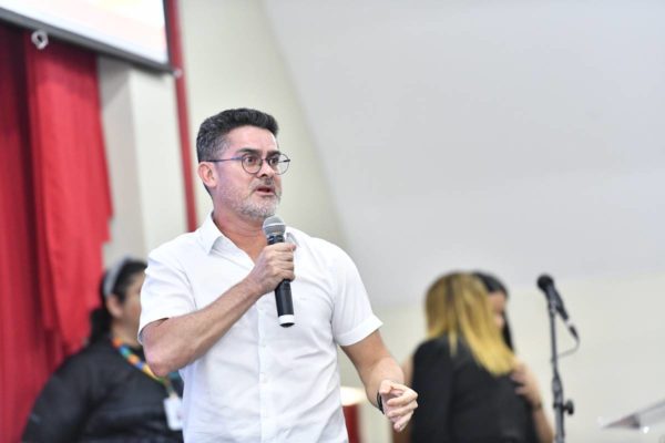 Fotografia colorida de homem discursando segurando microfone na mão
